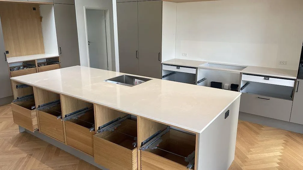 Köksbänkskiva i polerad Silestone Linen Cream, ljus kvartskomposit, med stor köksö och väggbänkar i ett kök i Hornslet.