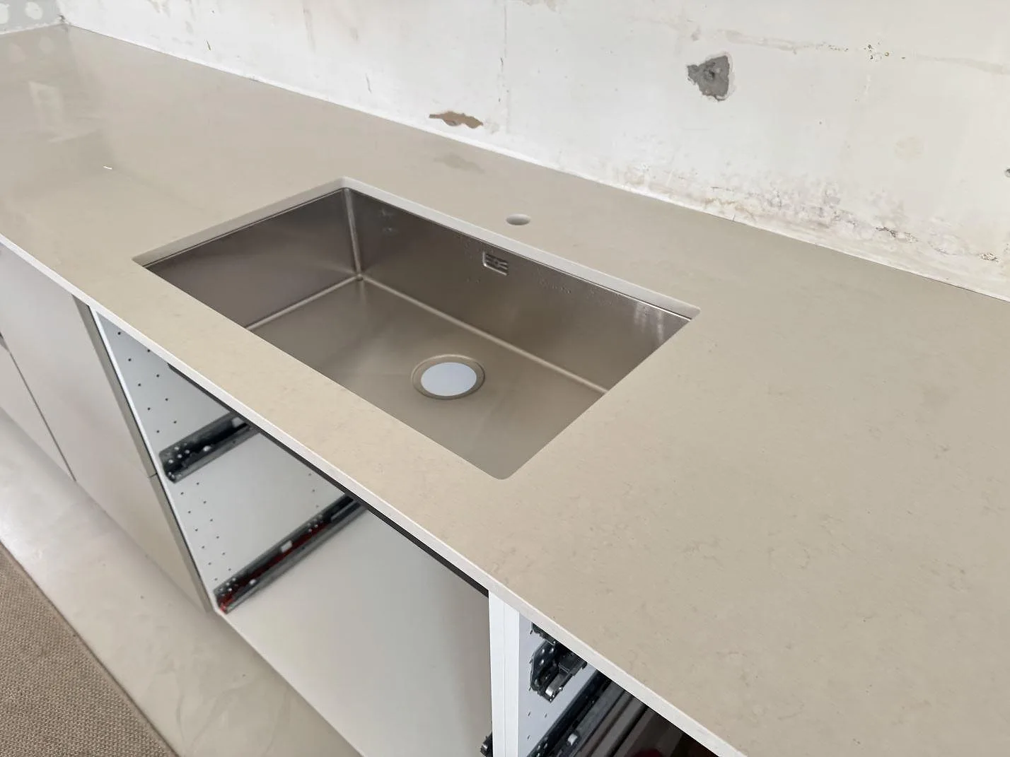 Närbild av polerad Silestone Linen Cream i ljus kvartskomposit runt en rostfri diskho i ett kök i Lomma.
