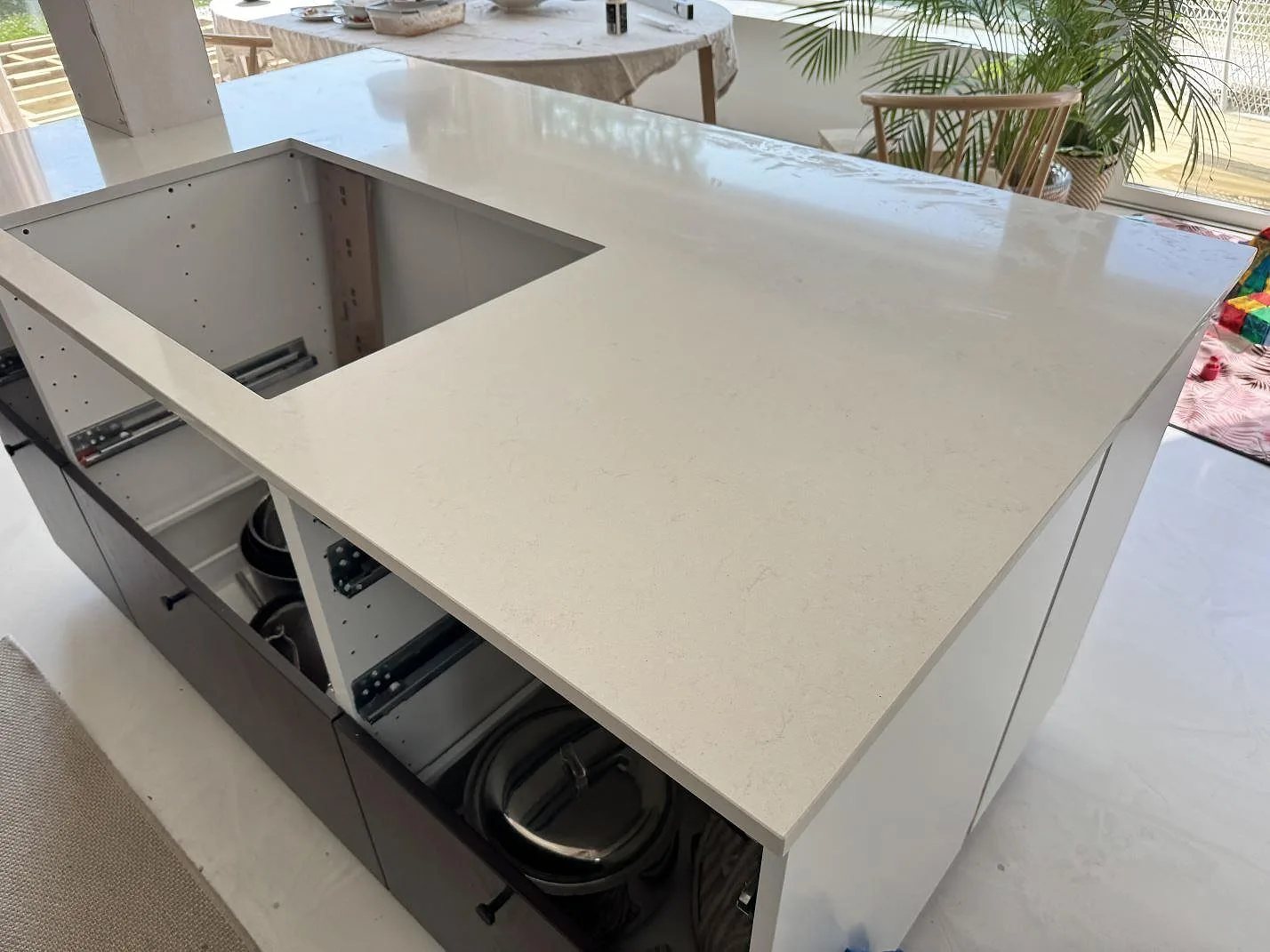 Stor köksbänkskiva i polerad Silestone Linen Cream, ljus kvartskomposit, med rektangulärt urtag över öppna köksstommar i Lomma.