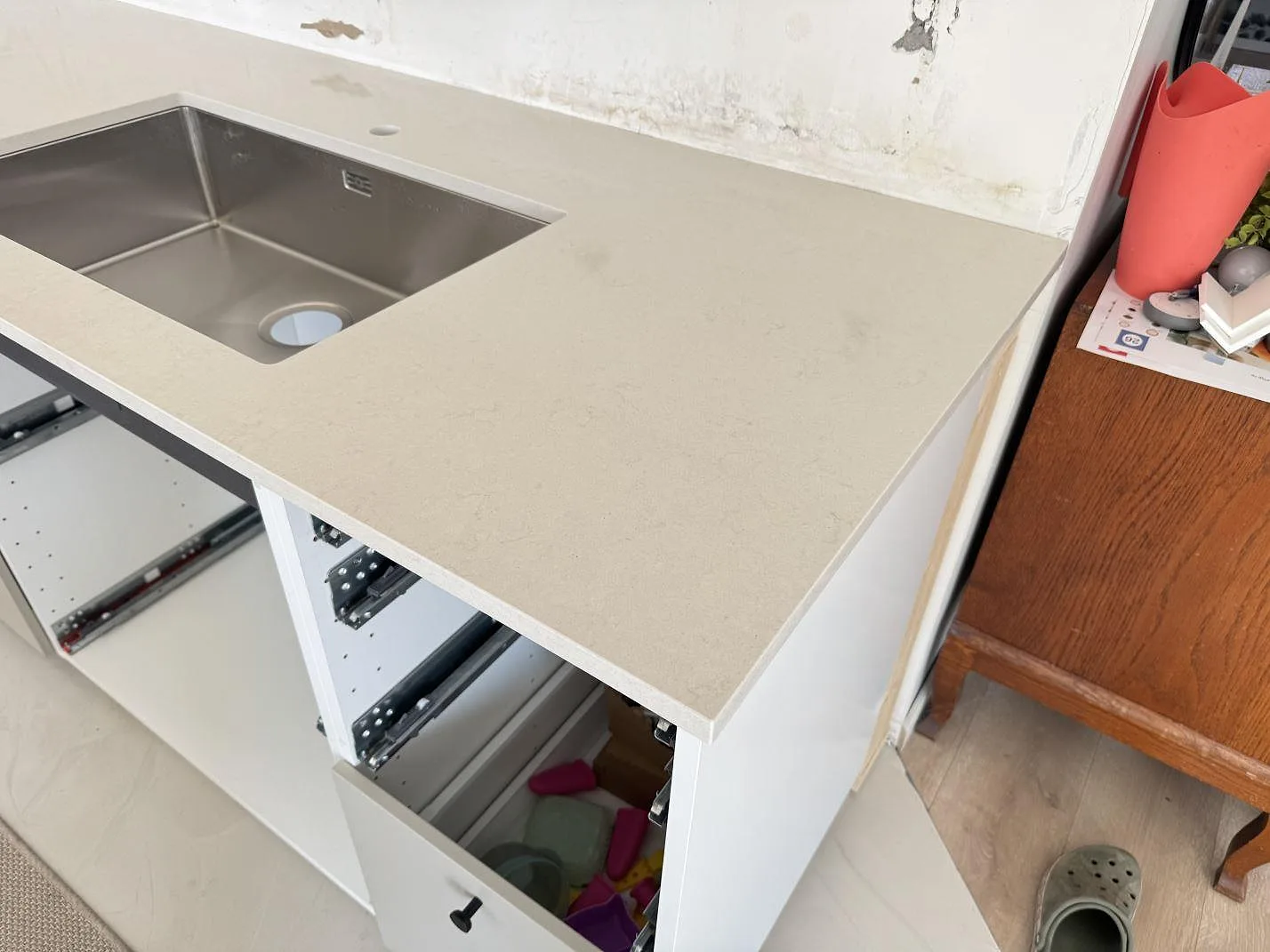 Köksbänkskiva i polerad Silestone Linen Cream, ljus kvartskomposit, med rostfri diskho och öppna kökslådor i Lomma.