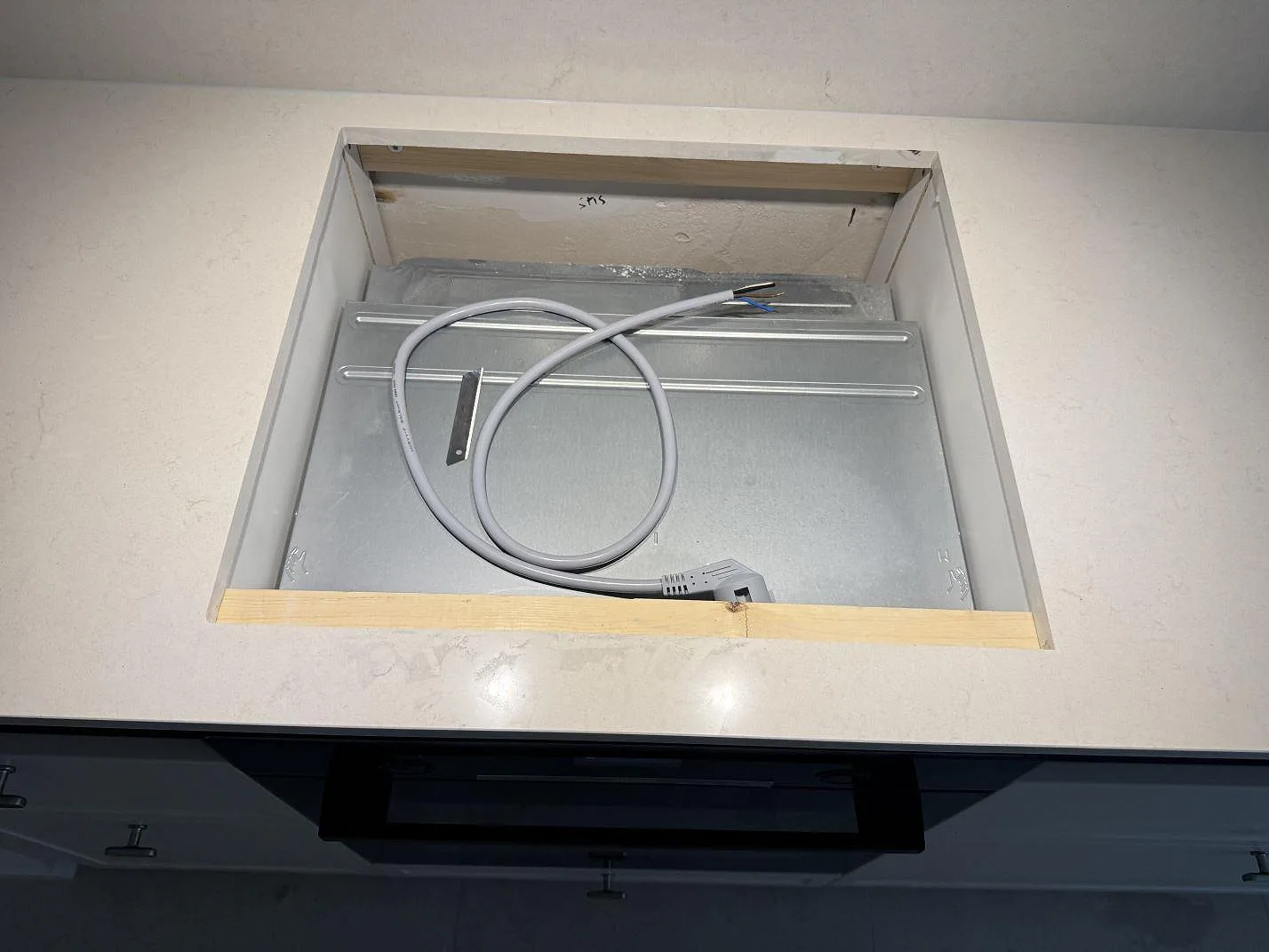 Närbild av hällöppning i polerad Silestone Linen Cream kompositbänkskiva under köksmontering i Lund.