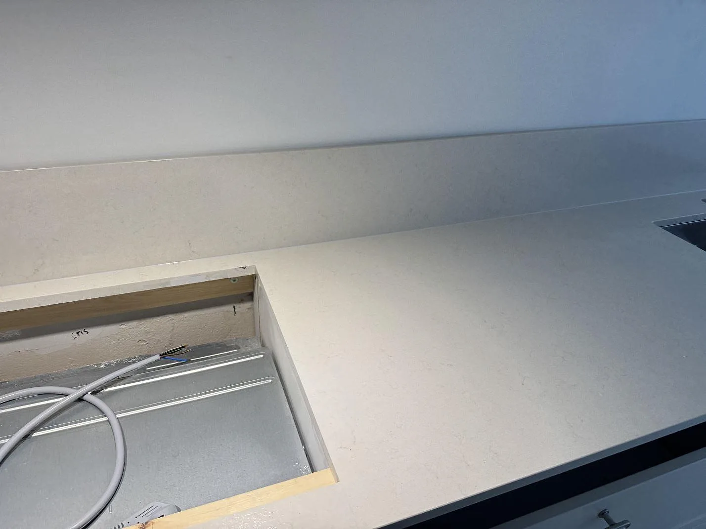 Polerad Silestone Linen Cream i kvartskomposit med förberedd hällöppning och lång köksbänk i Lund.