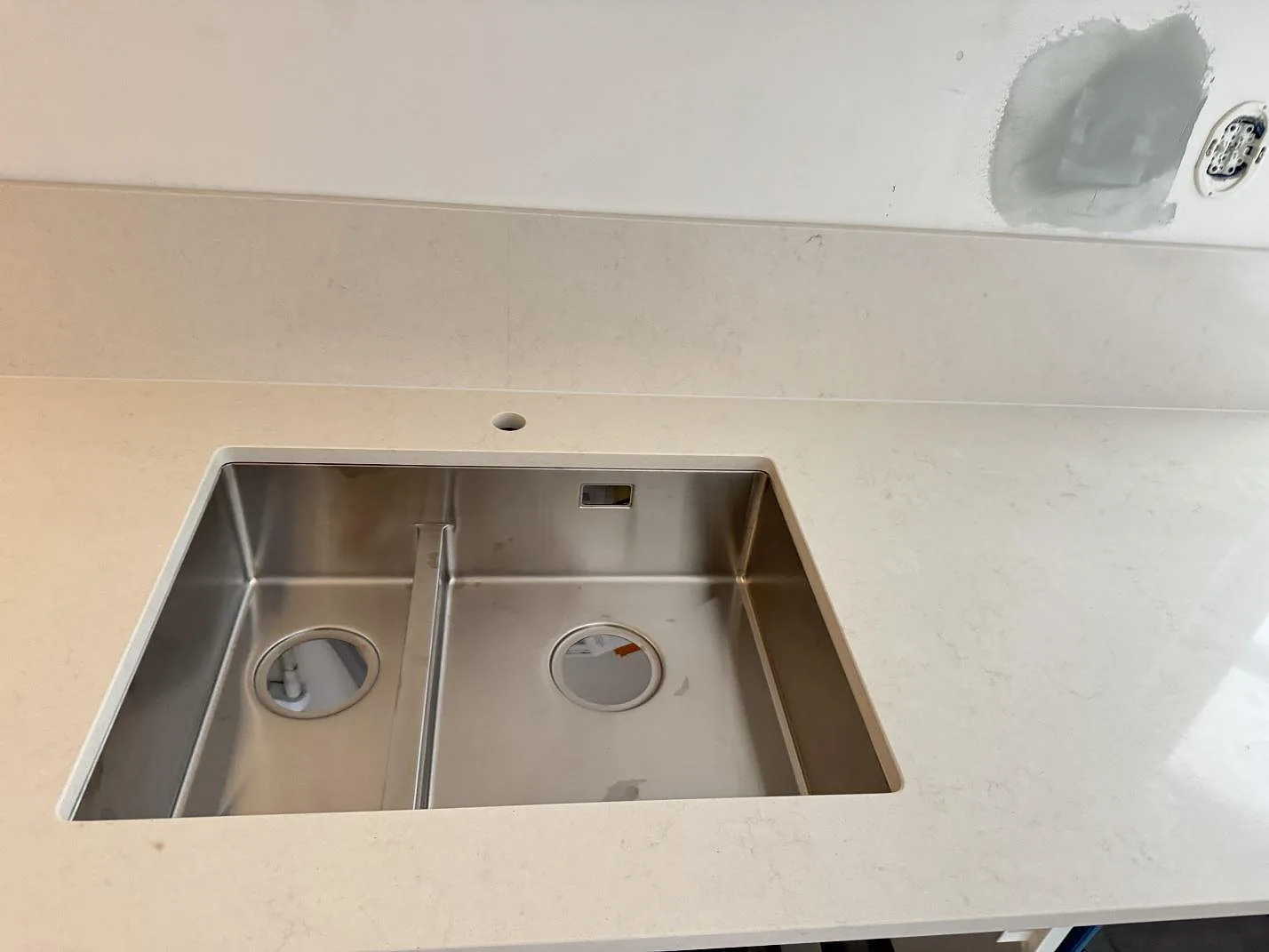 Rostfri diskho i polerad kompositbänkskiva av Silestone Linen Cream med stänkskydd i Lund.