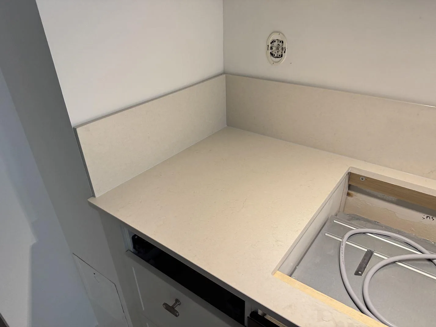 Hörndel av polerad kompositbänkskiva i Silestone Linen Cream med stänkskydd och hällöppning i Lund.