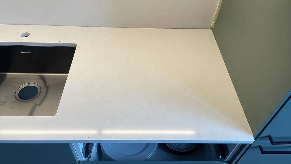 Höger bänkdel i köket i Malmö med polerad Silestone Linen Cream, ljus kvartskomposit, bred arbetsyta och rostfri diskho.