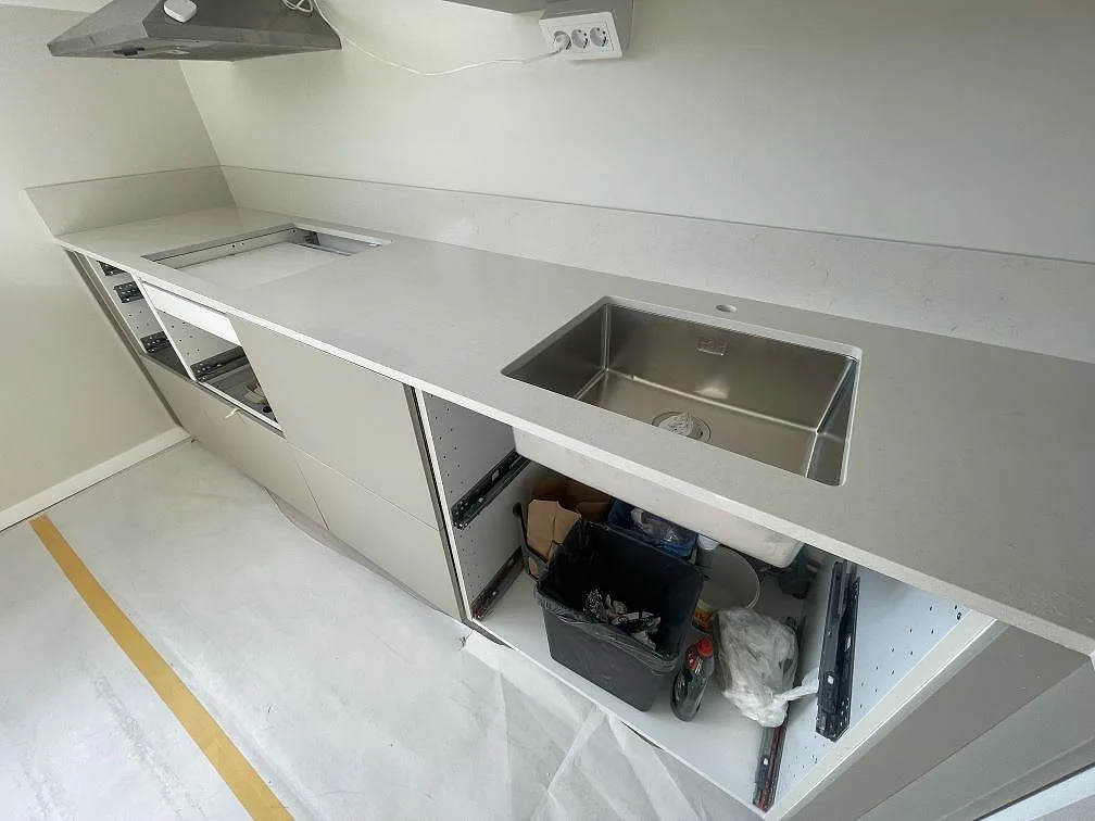 Polerad Silestone Linen Cream köksbänkskiva med rostfri diskho, hällurtag och stänkskydd längs väggen i ett kök i Rönninge.