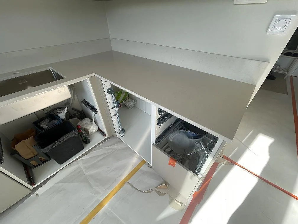 Hörnvy av köksbänkskiva i Silestone Linen Cream, polerad komposit, med rostfri diskho och ljus stänkskiva i Rönninge.