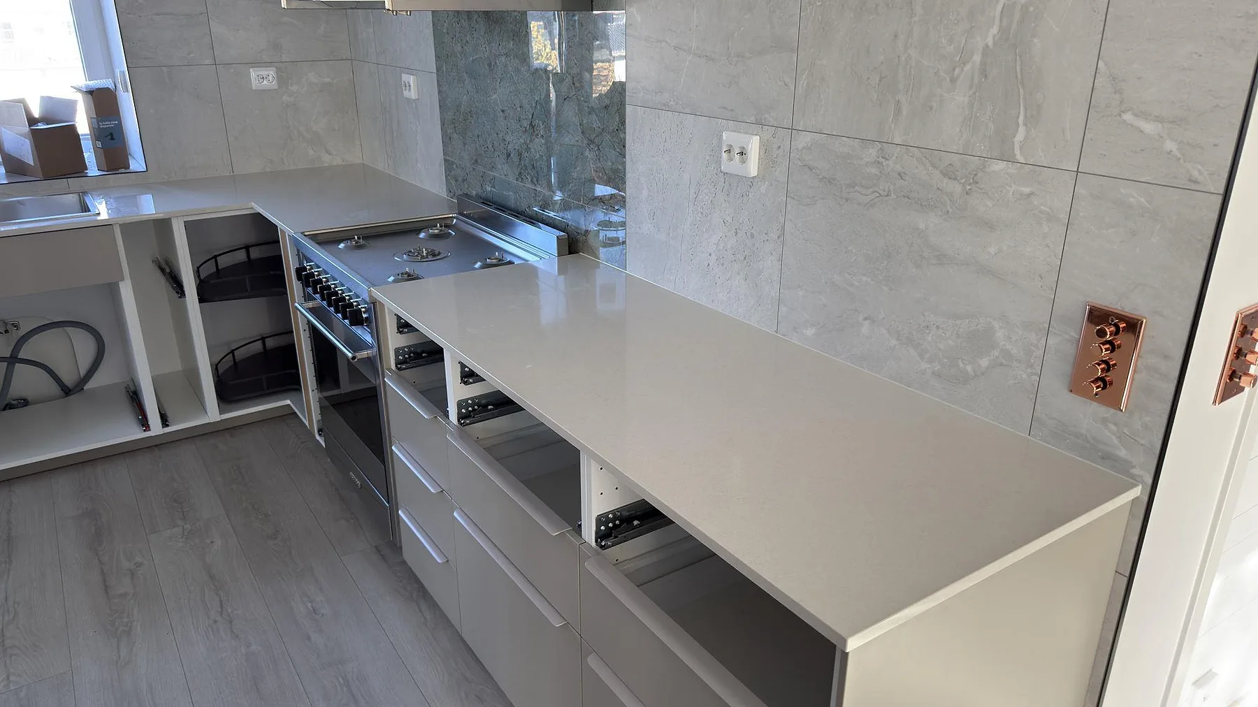 Polerad köksbänkskiva i Silestone Linen Cream med lång arbetsyta längs kaklad vägg i ett kök i Södertälje.