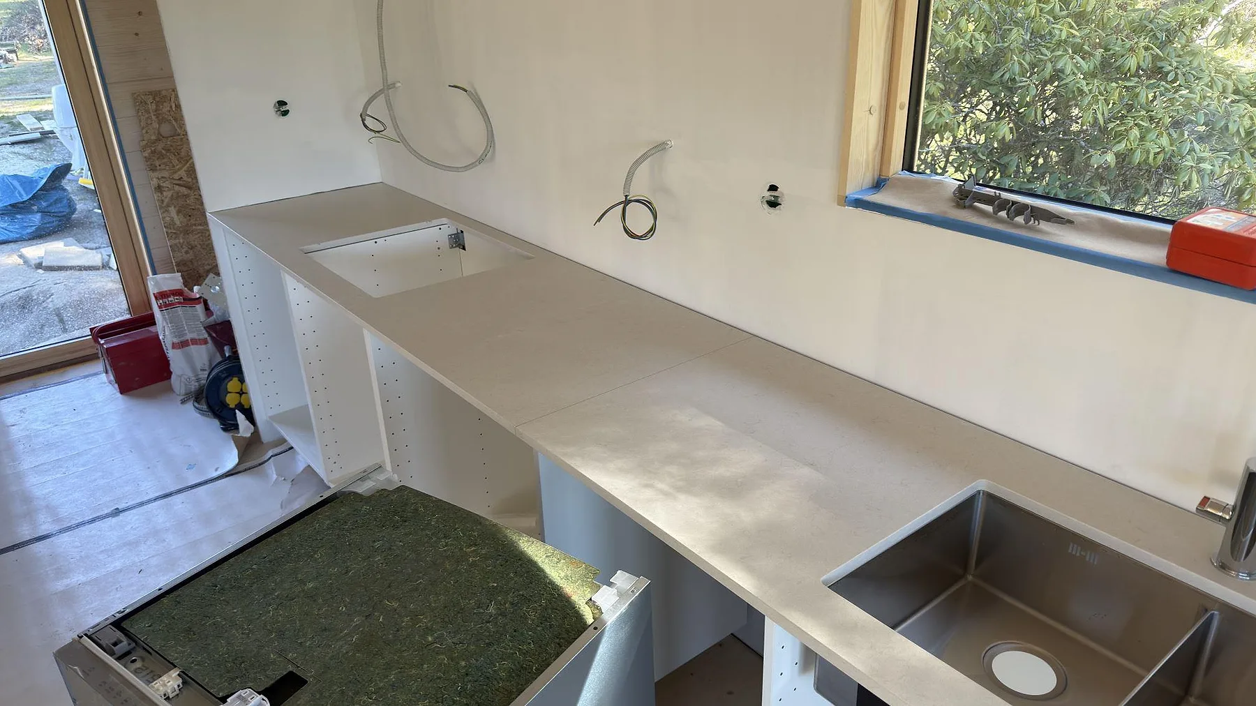 Matt Silestone Linen Cream-bänkskiva i L-form med en andra underlimmad rostfri diskho i returen, kök i Sorunda under montering.