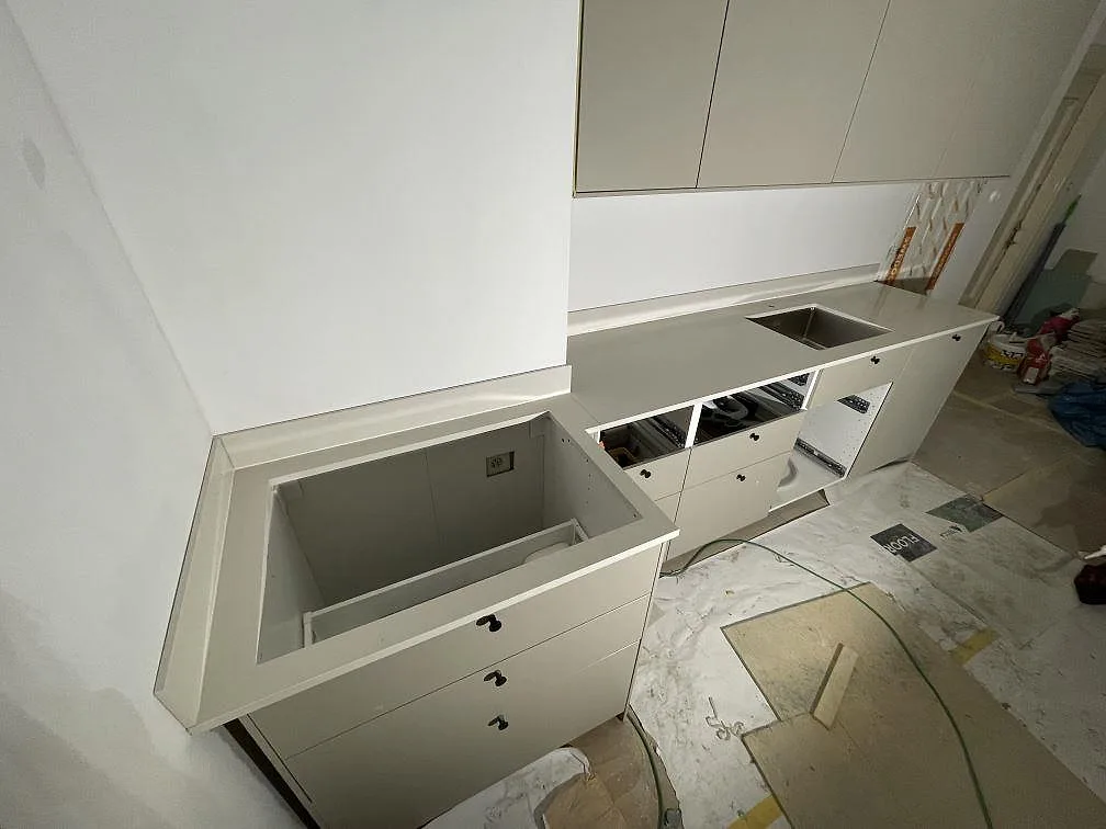 Polerad Silestone Linen Cream som bänkskiva och stänkskydd längs en köksrad med förberedd öppning och rostfri diskho i Stockholm.