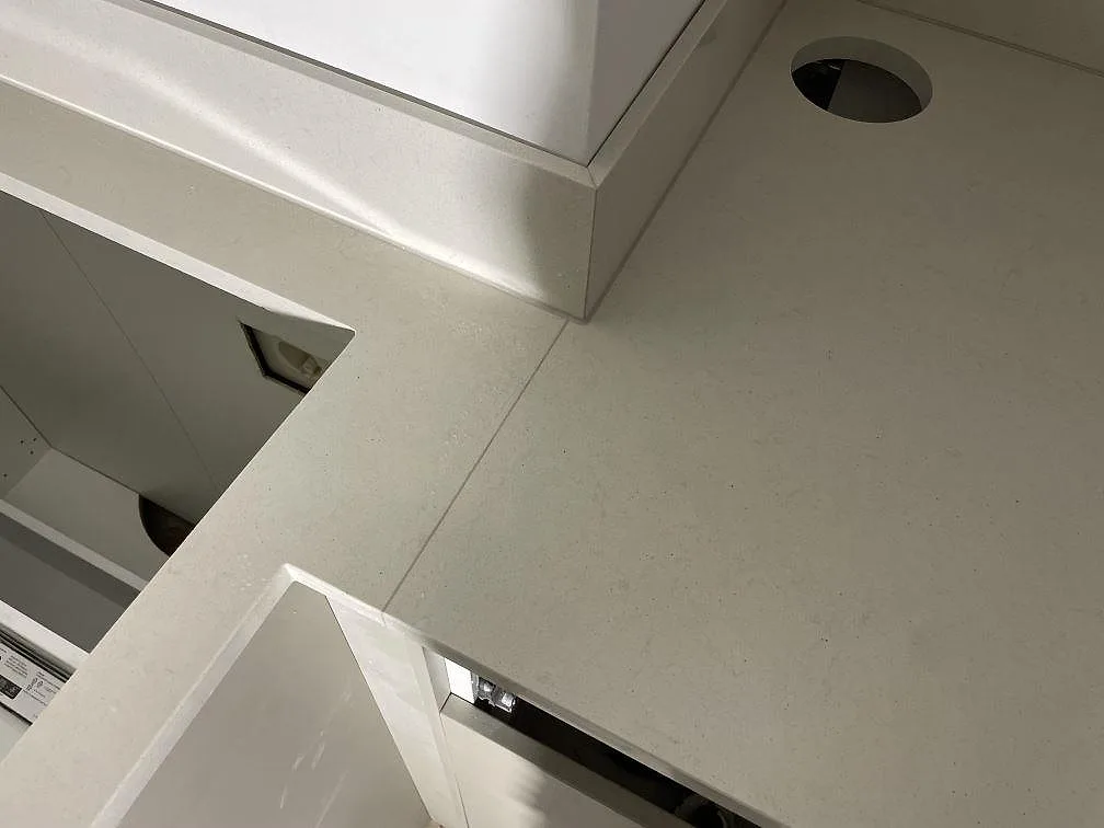Närbild av polerad Silestone Linen Cream med mjuka skiftningar, runt hål och sammanfogad bänkskiva vid stänkkant i Stockholm.
