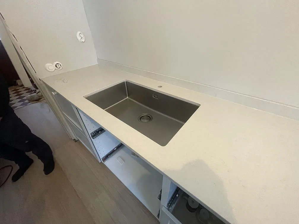 Undermonterad diskho i rostfritt stål i en bänkskiva av polerad Silestone Linen Cream i ett kök i Stockholm.