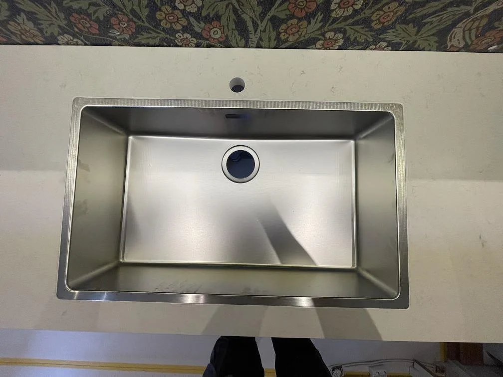Underlimmad rostfri diskho infälld i matt krämvit Silestone Linen Cream köksbänkskiva i ett kök i Stockholm.