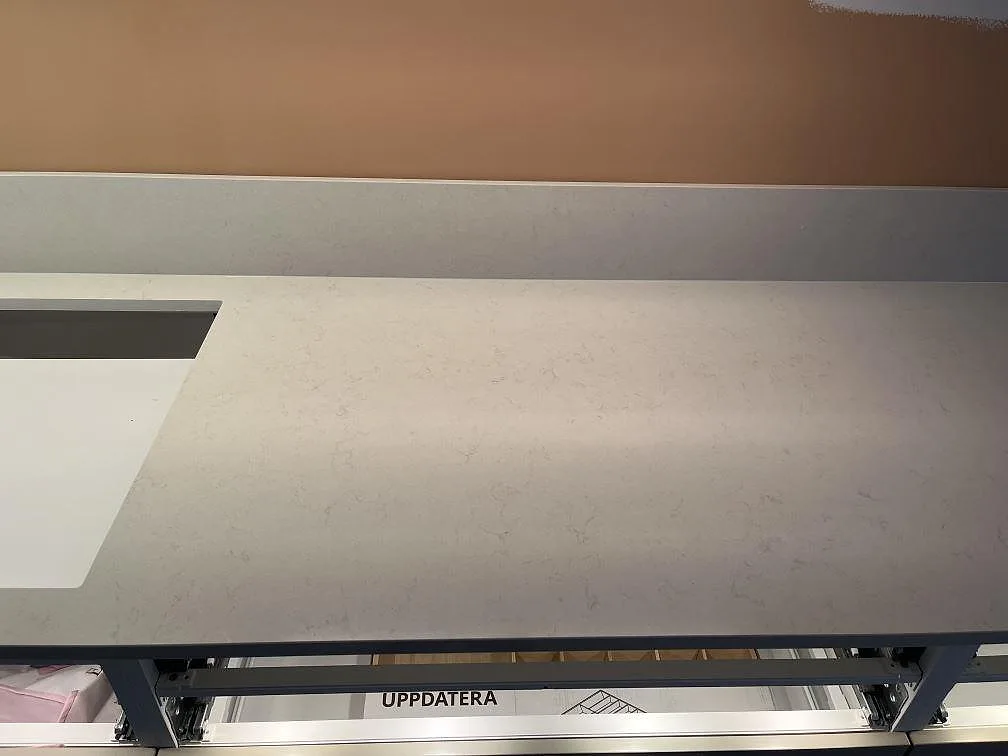Närbild på den mjukt ådrade ytan i polerad Silestone Linen Cream köksbänkskiva med urtagning, monterad över köksstommar i Täby.