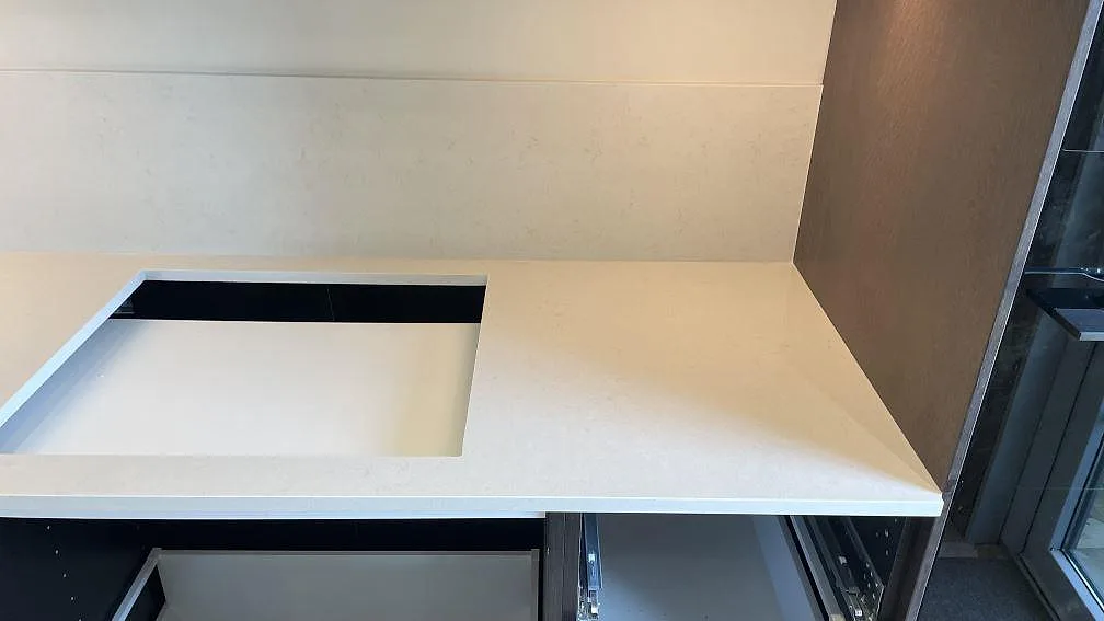 Väggbänk i polerad Silestone Linen Cream med hällöppning och stänkskydd i samma kompositsten i Tomelilla.