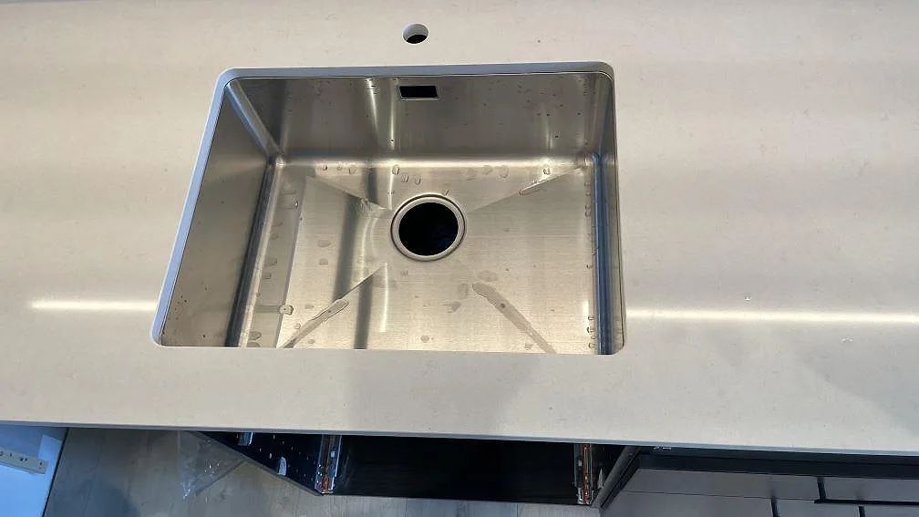Rostfri diskho i en polerad kompositbänkskiva av Silestone Linen Cream i ett kök i Tomelilla.