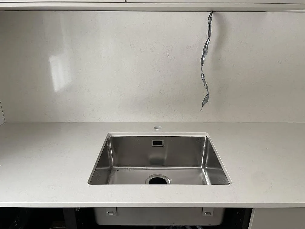 Underlimmad rostfri diskho monterad under en bänkskiva i polerad Silestone Linen Cream i ett kök i Tumba.