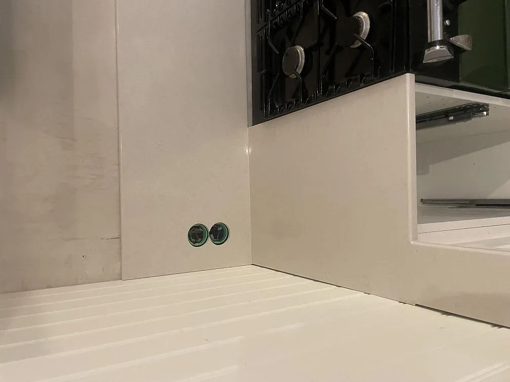 Närbild av uppvikt stänkkant i Silestone Linen Cream bredvid den fristående spisen i ett kök i Värmdö.