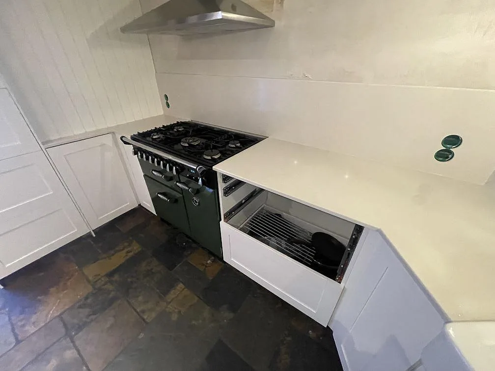 Hörnvinkel där köksbänkskivan i Silestone Linen Cream möter en fristående spis och skiffergolv i ett kök i Värmdö.