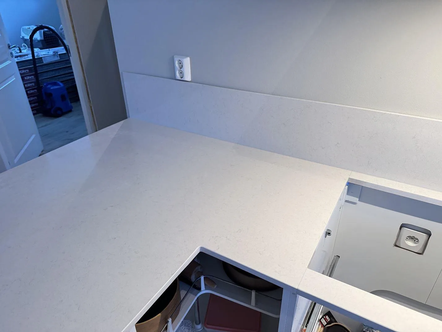 Polerad Silestone Linen Cream bänkskiva i hörn med mjuk reflektion och urtag, i ett kök under montering i Växjö.