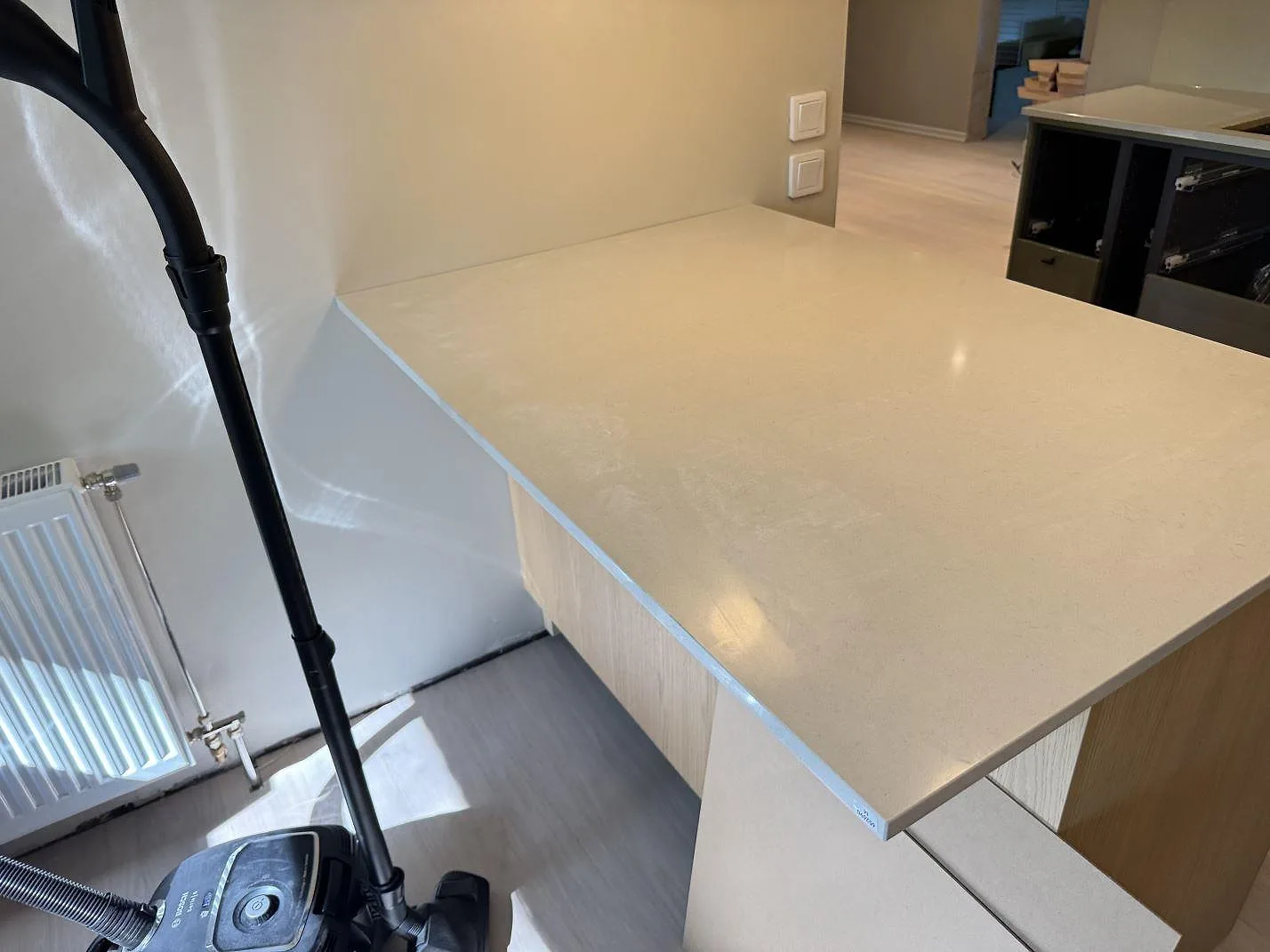 Polerad Silestone Linen Cream-bänkskiva sedd ovanifrån vid fönster och radiator i ett kök under montering i Veberöd.