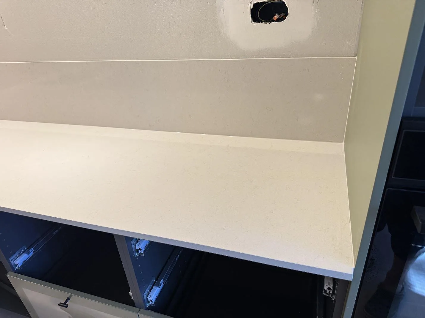 Rak arbetsyta i polerad Silestone Linen Cream, ljus komposit, med låg stänkkant och öppna stommar i Veberöd.