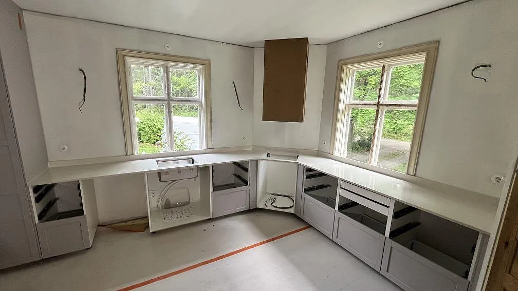 L-formad köksbänkskiva i polerad Silestone Linen Cream med rostfri diskho och uppvikt stänkkant i ett kök i Vittinge.