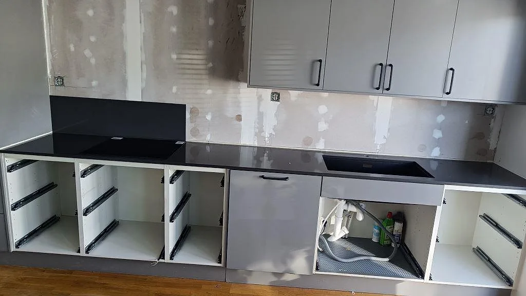 Köksbänkskiva i mörkt antracitgrå Silestone Marengo, polerad, med underlimmad kompositdiskho i ett kök under montering i Löddeköpinge.