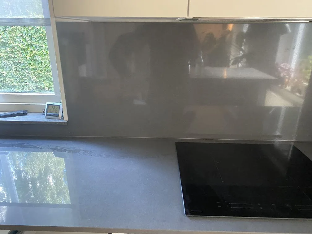 Köksbänkskiva i antracitgrå Silestone Marengo, polerad, med köksö, heltäckande stänkvägg och infälld induktionshäll i ett kök i Malmö.