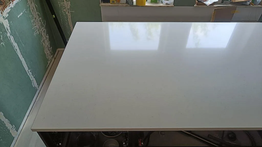 Köksö med blank vit Silestone Miami Vena i polerad kvartskomposit under montering i bunkeflostrand.