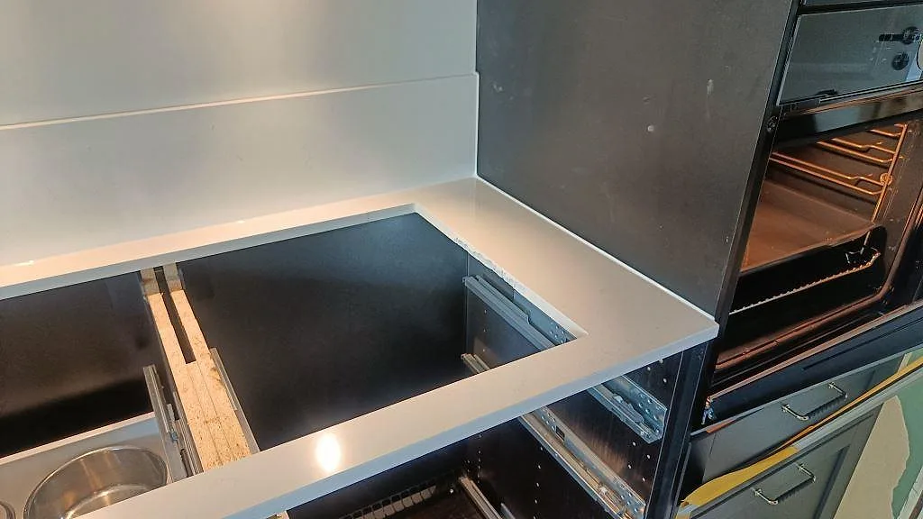 Polerad Silestone Miami Vena runt en utskärning i köksbänken intill mörka skåpstommar i bunkeflostrand.