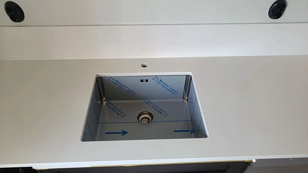 Underlimmad rostfri diskho i polerad Silestone Miami Vena med vit stänkkant i ett kök i bunkeflostrand.