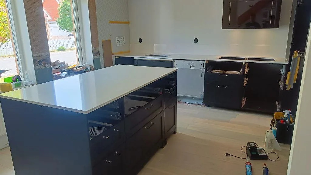 Köksbänkskiva i vit Silestone Miami Vena, polerad kvartskomposit, på köksö och väggbänk under montering i bunkeflostrand.