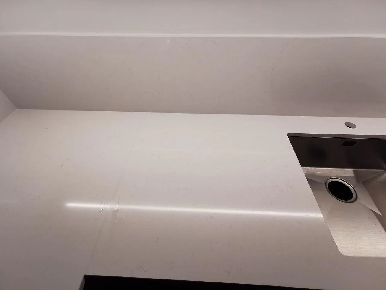 Närbild på polerad vit Silestone Miami Vena med rostfri diskho och uppvikt stänkkant i ett kök i Göteborg.