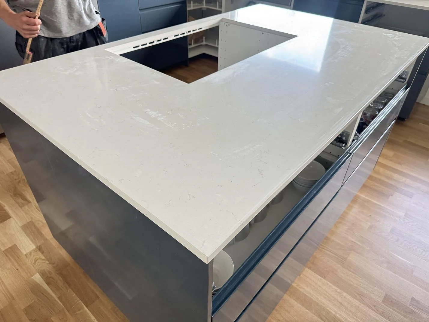 Polerad köksö i Silestone Miami Vena med ljus kvartskomposityta, diskret grå ådring och öppning för inbyggd utrustning i ett kök i Helsingborg.
