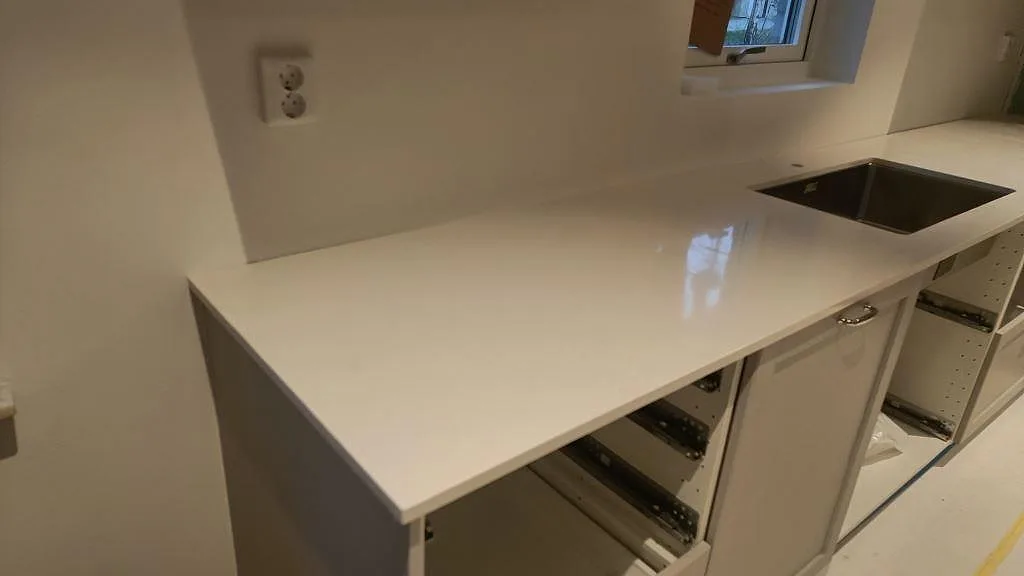 Närbild av polerad Silestone Miami Vena som köksbänkskiva med rostfri diskho under stenen i Höllviken.