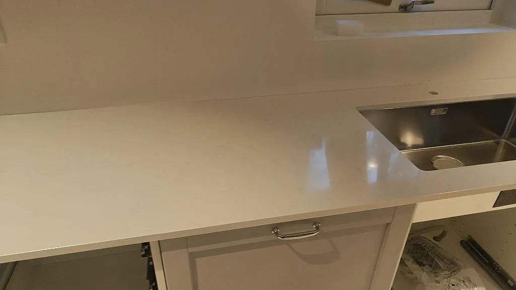 Polerad vit Silestone Miami Vena på köksbänk med underlimmad rostfri diskho och öppna stommar i Höllviken.