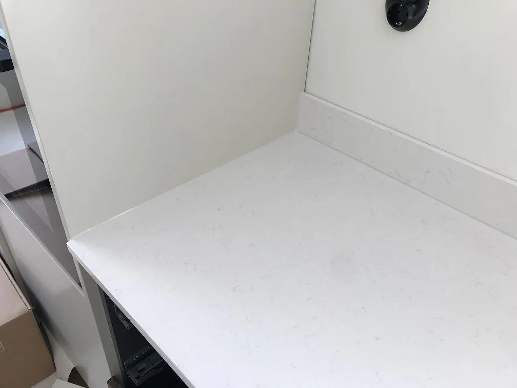 Hörn av bänkskiva i vit Silestone Miami Vena med uppvikt stänkkant mot vägguttag i ett kök i Karlshamn.
