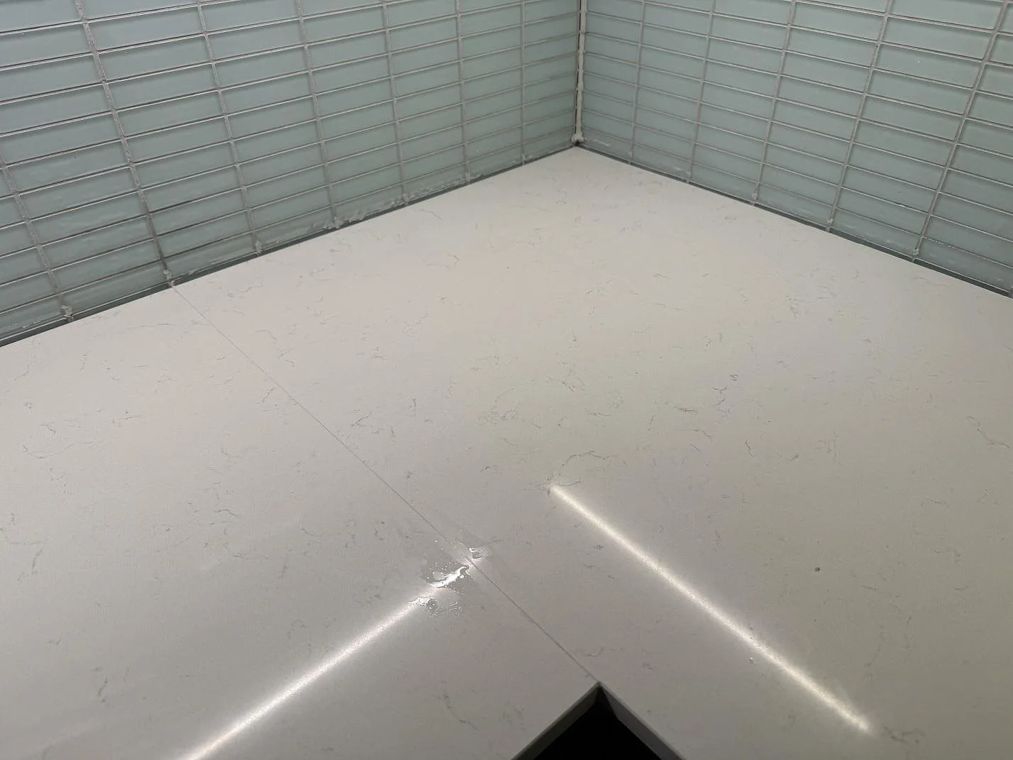 Hörndetalj av polerad Silestone Miami Vena kvartskomposit i Malmö, med ljus ådring, blank yta och kaklad vägg.