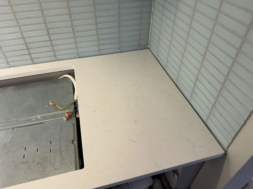 Sidobänk i polerad Silestone Miami Vena i Malmö vid öppning för spis eller häll, med köksväggens ljusa kakel bakom.