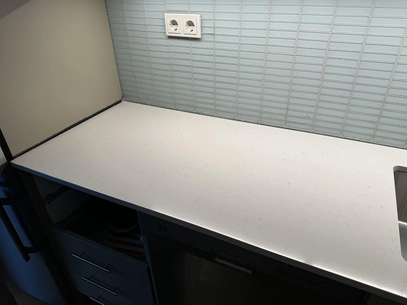 Lång arbetsyta i 20 mm polerad Silestone Miami Vena i Malmö, med vit komposityta, diskret grå ådring och kaklad vägg.