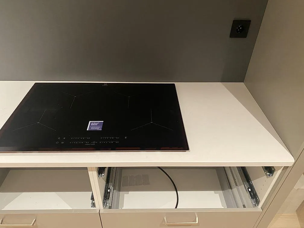 Detalj av induktionshäll i en ljus köksbänkskiva av polerad Silestone Miami Vena i Mariestad.