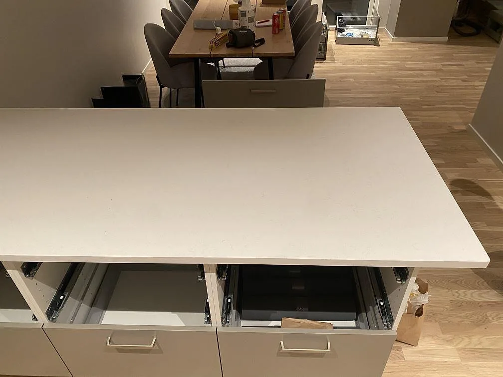 Köksö med polerad Silestone Miami Vena i ljus kvartskomposit och öppna köksstommar under montering i Mariestad.