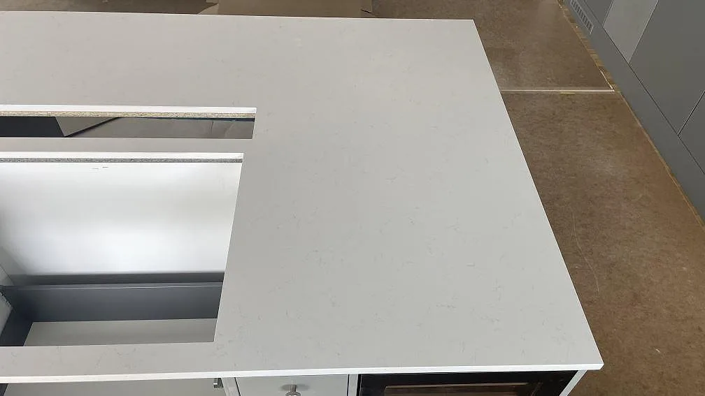 Detalj av vit polerad Silestone Miami Vena på köksö, kvartskomposit med diskret ådring och rak kant i Mölndal.
