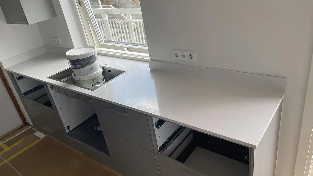 Väggbänk i polerad Silestone Miami Vena, vit kvartskomposit, med underlimmad rostfri diskho och låg stänkkant vid fönster i Mölndal.