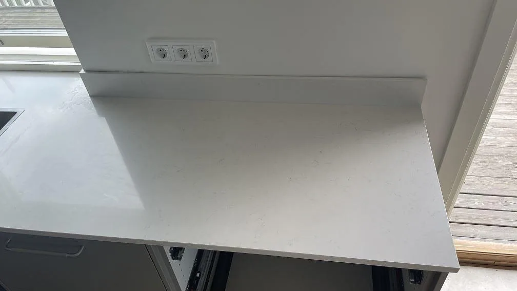 Polerad Silestone Miami Vena som väggbänk och låg stänkkant i vit kvartskomposit vid ett stort fönster i Mölndal.