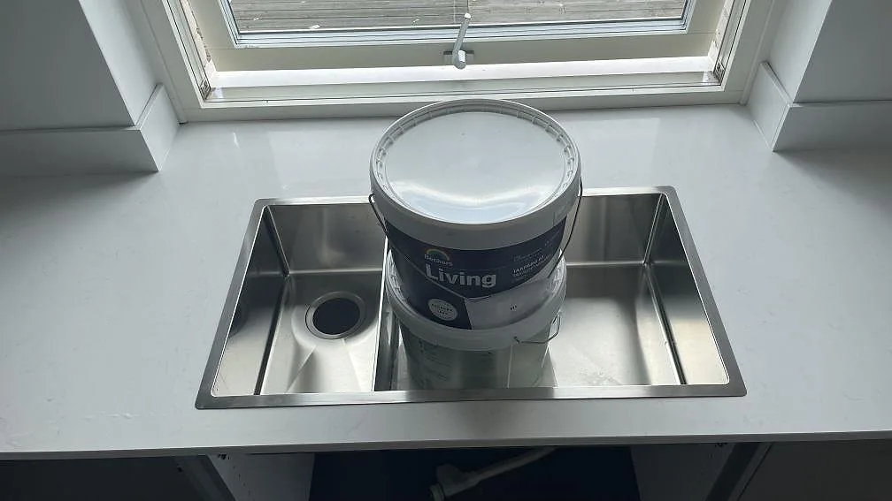 Underlimmad rostfri diskho i köksbänkskiva av polerad Silestone Miami Vena, vit kvartskomposit, framför fönster i Mölndal.