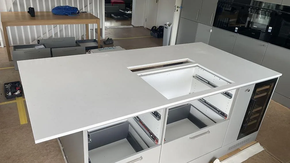 Stor köksö med köksbänkskiva i vit polerad Silestone Miami Vena, kvartskomposit, med öppning för häll i ett kök i Mölndal.