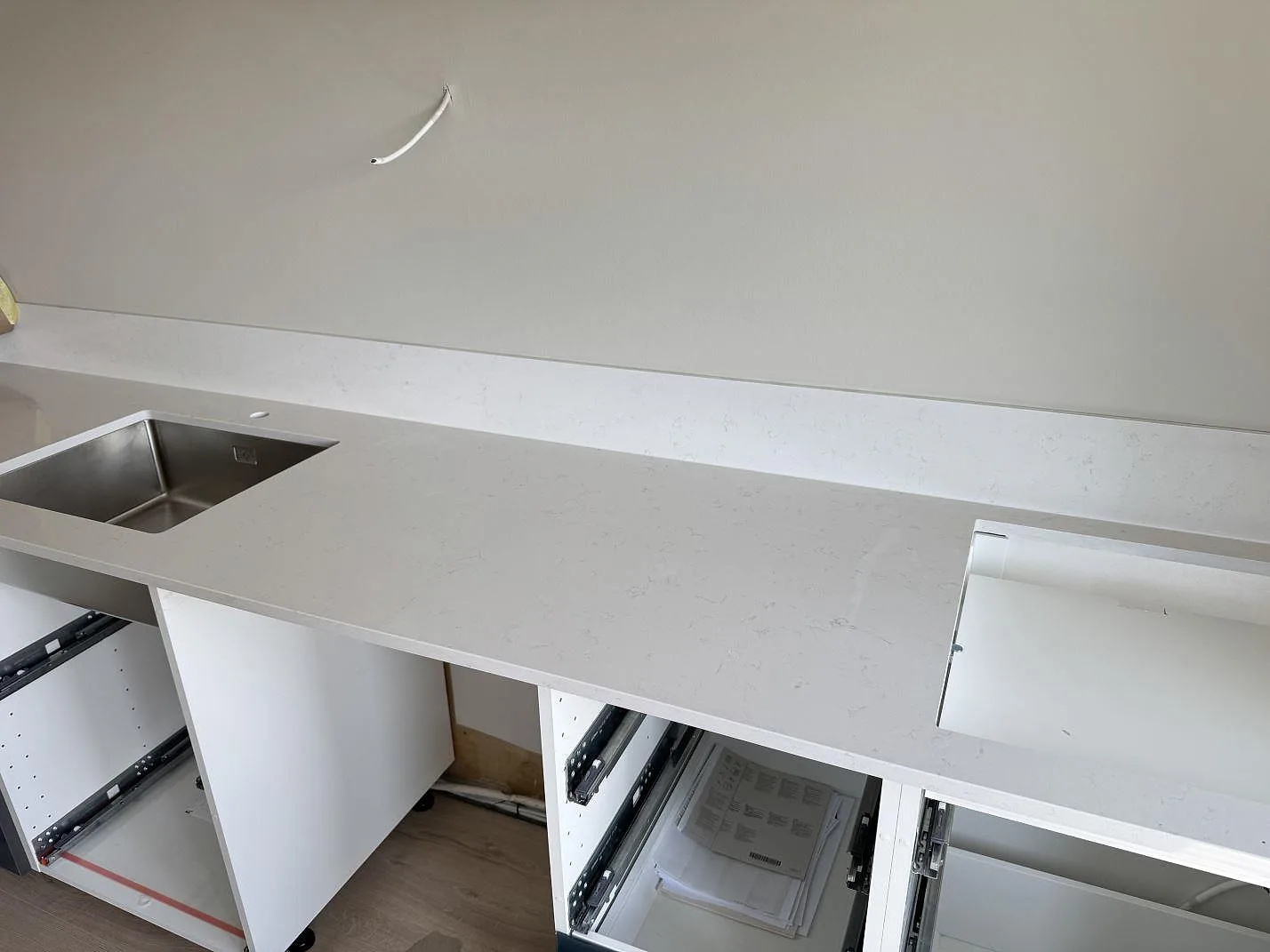 Lång köksbänk i polerad Silestone Miami Vena med rostfri diskho, förberedd öppning och ljus grå ådring i Staffanstorp.