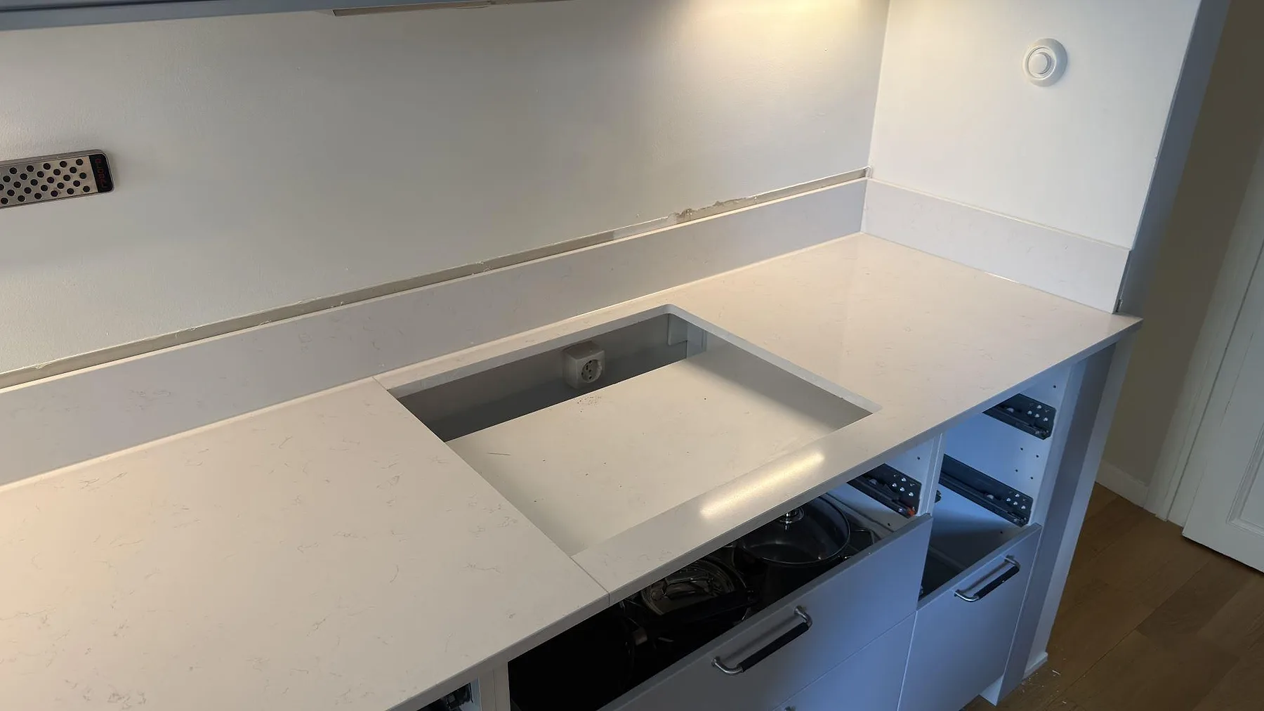 Bänkskiva i vit Silestone Miami Vena vid vinkyl och inbyggnadsugn, polerad komposit med diskret ådring i ett kök i Stockholm.